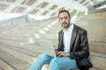 Young man working at computer sitting on stairs outside looking at camera Royalty Free Stock Photo