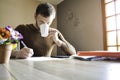 Young man working paperwork and bills at home and drinking coffee