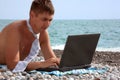 Young man working on his laptop on beach Royalty Free Stock Photo