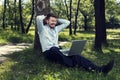 Young man working on his laptop in a public park and smiling Royalty Free Stock Photo