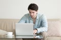 Young man working at home office, using laptop computer, freelan