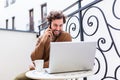 Young man working from home using smart phone and notebook computer.Portrait of businessman talking on mobile phone and drinking Royalty Free Stock Photo