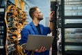 Young man is working with internet equipment and wires in server room Royalty Free Stock Photo