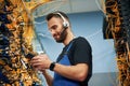 Young man is working with internet equipment and wires in server room Royalty Free Stock Photo
