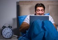 Young man working on laptop in bed