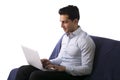 Young man working on laptop computer while sitting on couch