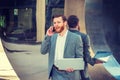 Young man working on laptop computer, talking on cell phone by mirror  on street in New York City Royalty Free Stock Photo