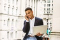 Young man working on laptop computer, talking on cell phone outside office building in New York City Royalty Free Stock Photo