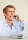 Young Man Working on Laptop Computer Talking on Phone Royalty Free Stock Photo