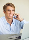 Young Man Working on Laptop Computer Talking on Phone Royalty Free Stock Photo