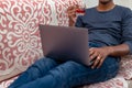 Young Man Working on Laptop with Glass of Red Wine and sitting on a couch Royalty Free Stock Photo