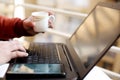 Young man is working on the laptop with holding tea cup in hand Royalty Free Stock Photo