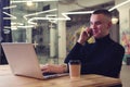 Young man working on laptop, talking on the phone and smiling. Royalty Free Stock Photo