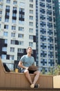 Young man working remotely outdoors sitting laptop coffee urban landscape Royalty Free Stock Photo