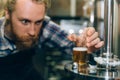 Young man working at small craft beer making factory and checking the quality of beer. Male working at beer plant.