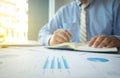 Young man working and writing in Book on his desk with financial Royalty Free Stock Photo