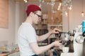 Barista stands behind the coffee machine and makes coffee