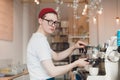Barista stands behind the coffee machine and makes coffee