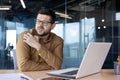 A young man works in the office on a laptop with documents. Feels an allergic reaction, itching and skin irritation. He Royalty Free Stock Photo