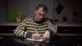 Young man writes on stickers his plans for the future, sitting at the kitchen table in the evening, planning things