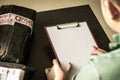 A young man writing on a blank paper with clipboard and with stack of delivery parcels as background Royalty Free Stock Photo