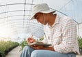 Profitability is an important business goal to plan for. a young man writing notes while working in a greenhouse on a Royalty Free Stock Photo