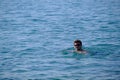 A young man of 25-30 years old swims in the sea in sunglasses on the surface there is only a head brunette thick hair