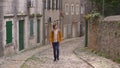 A young man in a yellow jacket is walking along the old street in the city of Risan or Risano. This city is considered