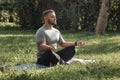 Young sporty man yogi sitting in lotus yoga pose in grass lawn park outdoors Royalty Free Stock Photo