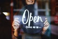 Young manager girl changing a sign from closed to open sign on door cafe Royalty Free Stock Photo