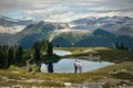 Young married couple hiking in mountains near beautiful alpine lakes and glaciers.