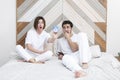 Young married couple lying on the bed and trying to turn off ringing alarm clock Royalty Free Stock Photo