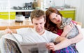 Young married couple in pajamas sitting in the sofa with newspaper and cat at home Royalty Free Stock Photo