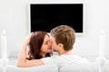 Young married couple sitting on the couch and watching tv at home, rare view, with space for text Royalty Free Stock Photo