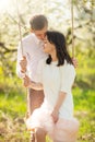 Young married couple, on a swing in a flowered garden or park. Warmly, love, spring and summer mood Royalty Free Stock Photo