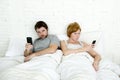 young married couple using their mobile phone in bed ignoring each other in relationship communication problems Royalty Free Stock Photo