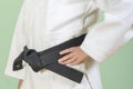 White judo gi. A young martial arts master knots a black belt.