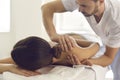 Young masseur in physiotherapy center massaging woman`s shoulder, easing pain and relaxing muscles