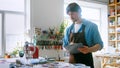 A young master conducting inventory in a creative studio. A man in an apron with clipboard