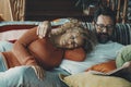 Young mature couple at home having relax and resting together on the sofa. Man reading a book and woman sleeping on him. Love and Royalty Free Stock Photo