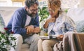 Young mature couple reading together a memories book diary outside home in the terrace sitting on couch. Happy man and woman