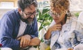 Young mature couple reading together a memories book diary outside home in the terrace sitting on couch. Happy man and woman