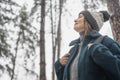 A young mature woman breathes fresh air and enjoys the snowfall in the winter forest. Winter walks and activity concept