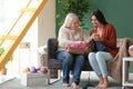 Young and mature women with knitting yarn sitting on sofa indoors Royalty Free Stock Photo