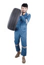 Young mechanic carrying a tire in the studio Royalty Free Stock Photo