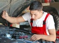 Young mechanic checking engine oil level in car service center Royalty Free Stock Photo