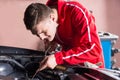 Young mechanic checking the oil level in a car engine Royalty Free Stock Photo