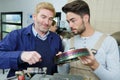 Young mechanic holding part and talking with tutor Royalty Free Stock Photo