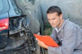 Young mechanic inspecting damaged car