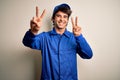 Young mechanic man wearing blue cap and uniform standing over isolated white background smiling looking to the camera showing Royalty Free Stock Photo